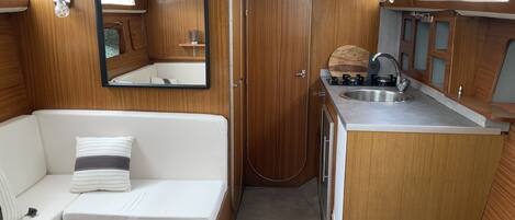 A compact RV interior with a kitchenette, a seating area, and a small table.