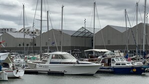Een jachthaven met verschillende boten afgemeerd, een gebouw met schuin dak en een bewolkte lucht.
