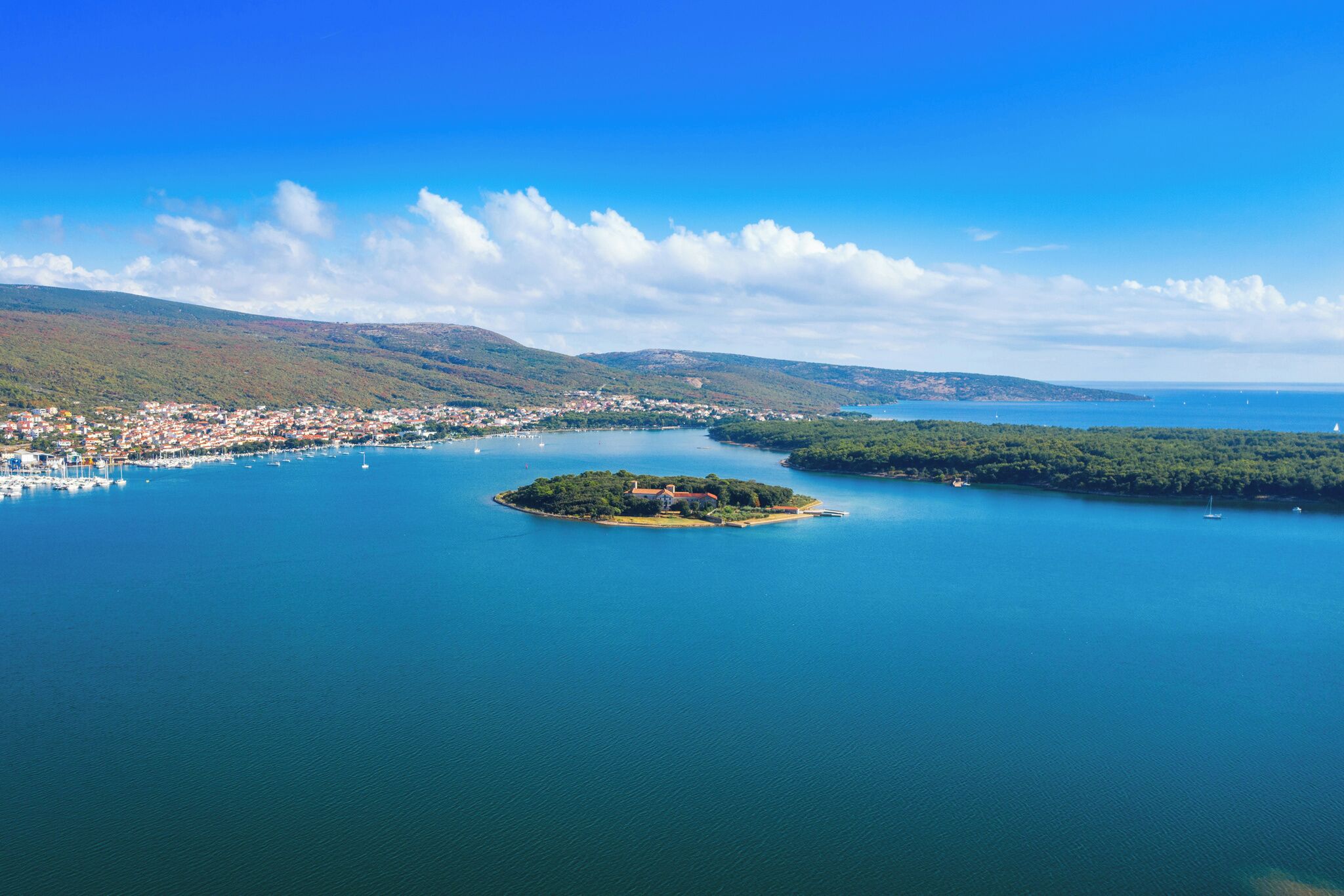 Vista aérea de un pueblo costero con una pequeña isla que presenta un edificio destacado.