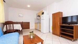 A compact living space with a dining area, kitchenette, and a TV stand.