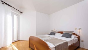 Une chambre à coucher avec un lit en bois, une fenêtre avec des rideaux et un interrupteur sur le mur.