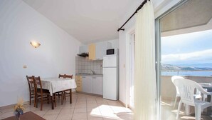 Une petite cuisine lumineuse avec un coin repas et un balcon offrant une vue agréable.