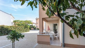 Un immeuble résidentiel doté d’un patio aménagé avec du mobilier d’extérieur et un petit arbre.