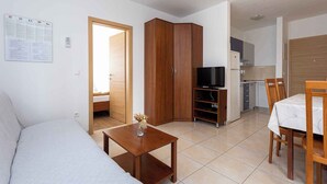 Un espace de vie compact comprenant un canapé, un meuble en bois, un support pour télévision et un coin repas.