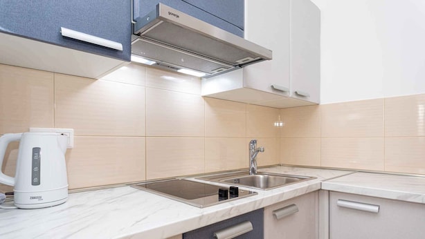 Une cuisine moderne équipée d’une cuisinière intégrée, d’un évier et d’une bouilloire.