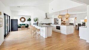 A spacious kitchen with a large island, white cabinetry, and wooden flooring. - NEW Waterfront, private dock, fully updated Johns Island home (Johns Island)