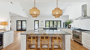 A spacious kitchen with a large island, stainless steel appliances, and wicker chairs. - NEW Waterfront, private dock, fully updated Johns Island home (Johns Island)
