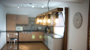 A modern kitchen with a wooden countertop, a dining area with a table and chairs, and a hanging light fixture.