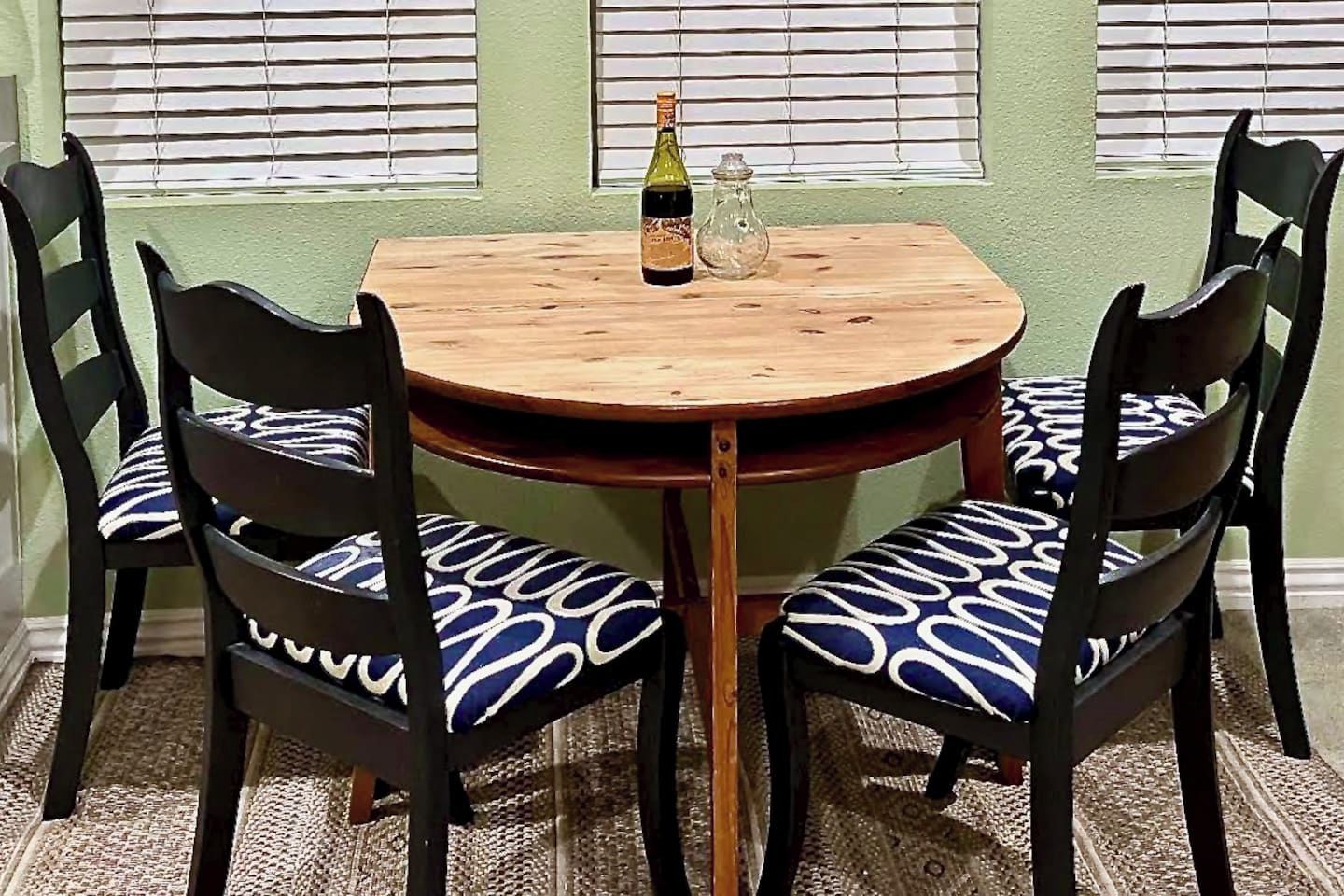 Une table ronde en bois, accompagnée de deux chaises, chacune dotée d’un coussin à motifs.