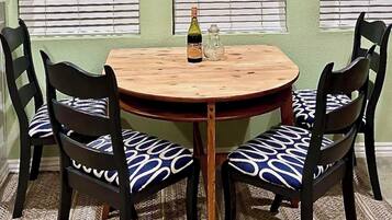 Une table ronde en bois, accompagnée de deux chaises, chacune dotée d’un coussin à motifs.
