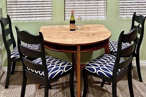 Une table ronde en bois, accompagnée de deux chaises, chacune dotée d’un coussin à motifs.