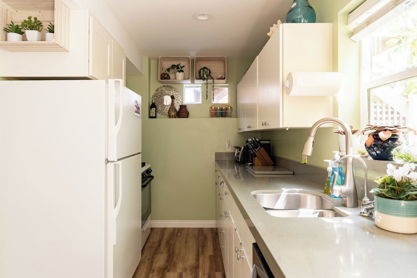 A compact kitchen with white cabinets, a stainless steel sink, and a built-in oven.
