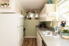 A compact kitchen with white cabinets, a stainless steel sink, and a built-in oven. - Stylish Spacious Seaside Retreat, Walking to Beach (Half Moon Bay)