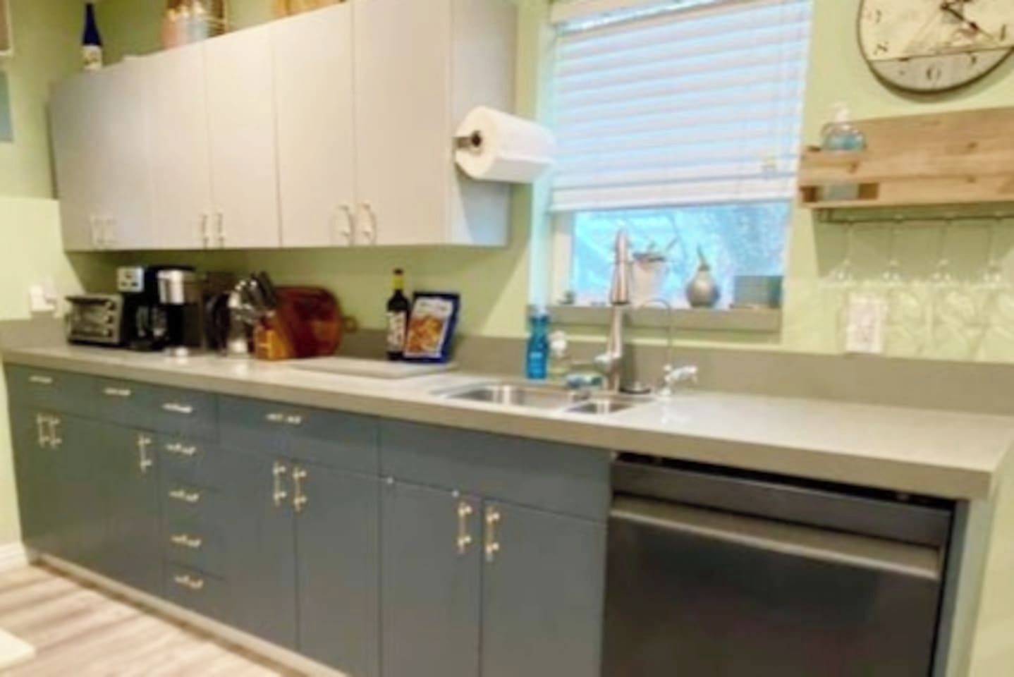 Una cocina con lavavajillas integrado, un lavabo y una ventana con persianas.