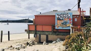 Een restaurant aan het strand met een bord waarop zeevruchten staan aangeboden en uitzicht op de oceaan.