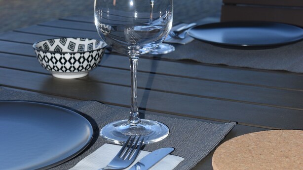 Une table dressée pour deux personnes, avec un verre à vin et un bol, donnant sur un paysage montagneux.