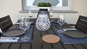 Une table à manger dressée avec des assiettes, des couverts et des verres à vin, agrémentée d’une lanterne décorative placée au centre.