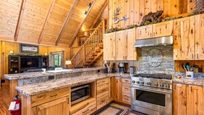 Una cocina amplia con armarios de madera, encimeras de granito y una estufa de acero inoxidable, además de una isla grande.
