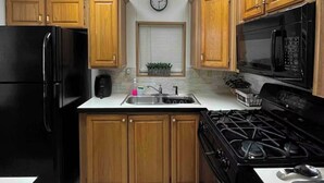 A modern kitchen with wooden cabinets, a black refrigerator, a stove, and a microwave. - Perfect Place for a Perfect Vacation (Kissimmee)