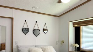 A bedroom with a bed, a ceiling fan, and three heart-shaped wall decorations. - Perfect Place for a Perfect Vacation (Kissimmee)