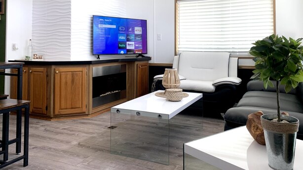 A modern living room with a flat-screen TV, a sofa, a coffee table, and a ceiling fan. - Perfect Place for a Perfect Vacation (Kissimmee)