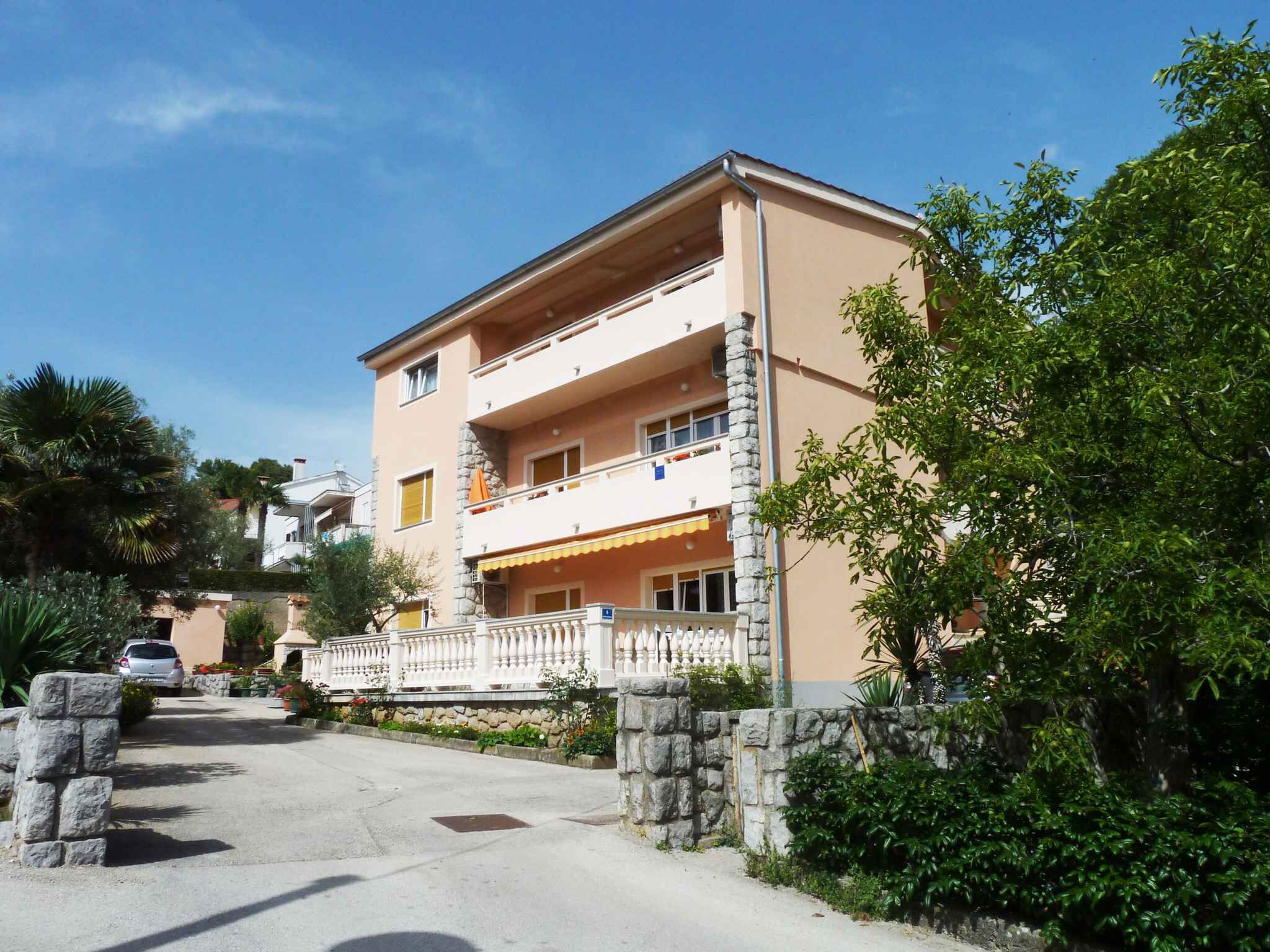 Un edificio a più piani con balconi, un muro in pietra e un vialetto lastricato.