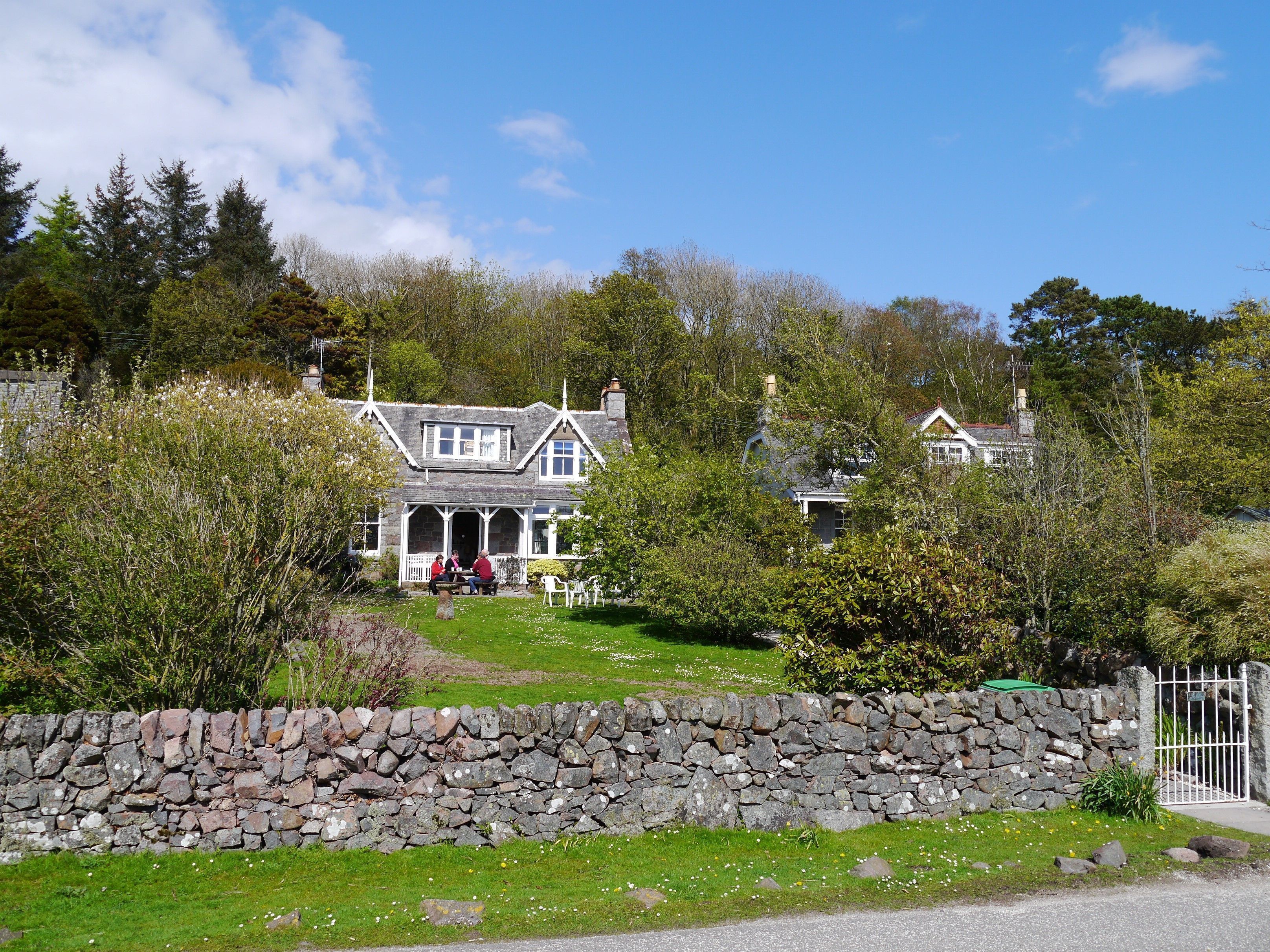 A stone wall, a grassy area, and a building with a porch.