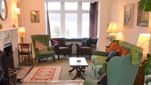 Un salón acogedor con una mesa de comedor de madera, sillones verdes, un sofá y una chimenea.