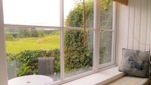 Asiento junto a la ventana con vistas a un paisaje verde.