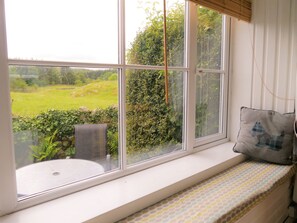 Asiento junto a la ventana con vistas a un paisaje verde.