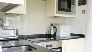 Una cocina moderna con un tostador de acero inoxidable, una tetera, un microondas y un panero.