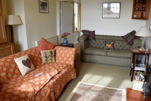 A living room with two sofas, a patterned rug, and a lamp.