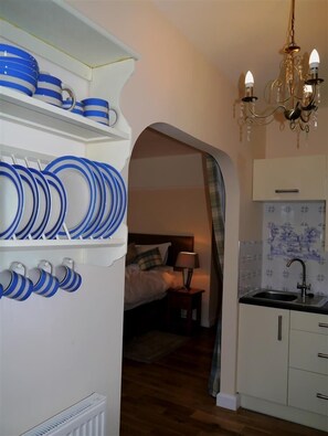 A compact kitchen with white cabinets, a sink, and a chandelier.