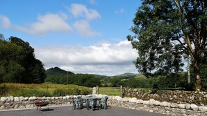 A paved outdoor area with stone walls, a metal gate, and a table with chairs. - Rusko Stables -  an apartment that sleeps 6 guests  in 3 bedrooms (Gatehouse Of Fleet)