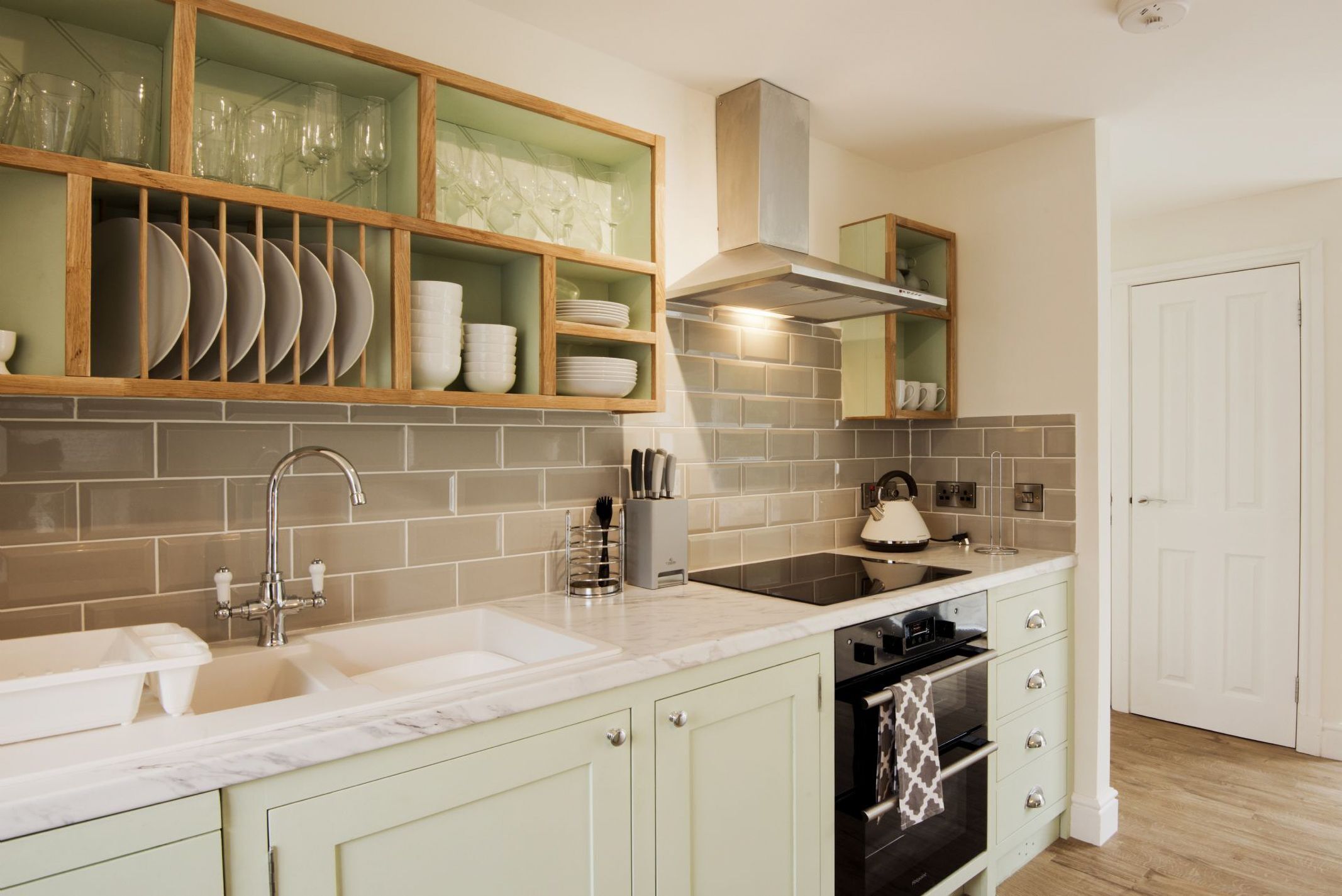 A modern kitchen with a double sink, a stove, and a built-in oven.