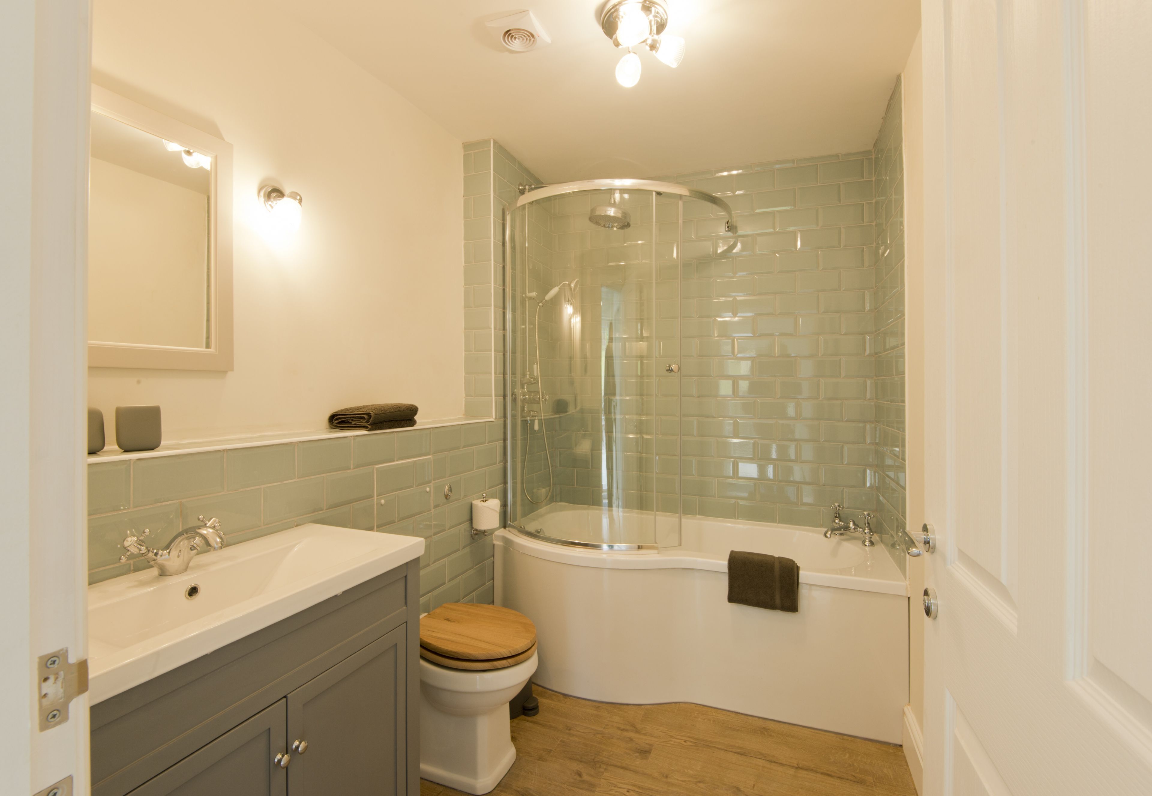 Une salle de bain moderne avec une douche à parois de verre, un lavabo blanc et des toilettes en bois.