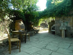 An outdoor patio with stone flooring, a wooden table, and chairs.