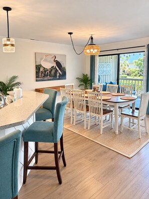 A modern dining area with a large table, chairs, and pendant lighting.