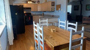 A kitchen with wooden cabinets, a dining table with white chairs, and a ceiling fan.