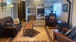 A cozy living room with a leather sofa, a wooden coffee table, a bookshelf, and a fireplace.