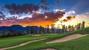 Ein Golfplatz mit blauem Himmel und Bergen im Hintergrund.
