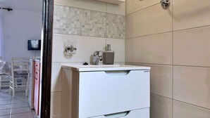 Un bany amb un lavabo blanc, un dispensador de sabó de vidre i un mirall damunt del lavabo.