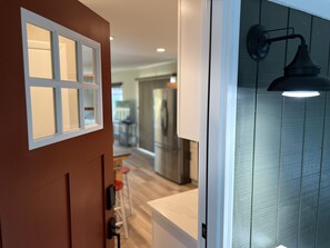A hallway with a door leading to a kitchen area. - Waterfront, Stunning Views, Private Beach, and Close To Concerts (Quincy)