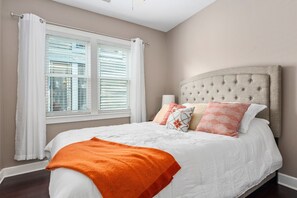 A bedroom with a large bed, white bedding, and a beige headboard.
