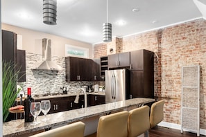 A modern kitchen with dark wood cabinets, a stainless steel refrigerator, and a granite countertop.