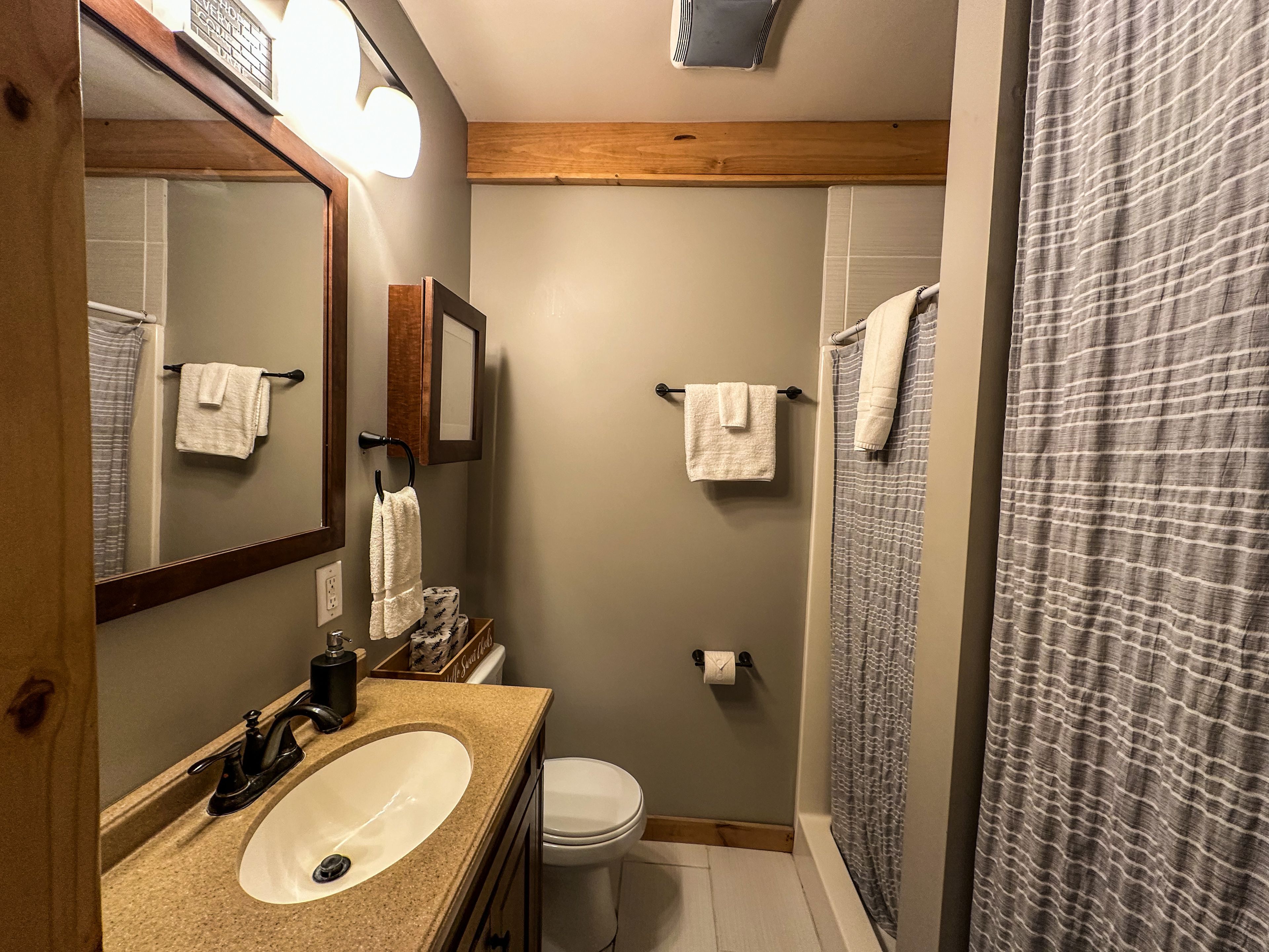 A bathroom with a sink, mirror, towel rack, toilet, and shower curtain.
