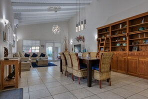Een ruime woonkamer met een eethoek, een grote houten boekenkast en een televisie.