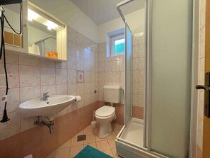 A bathroom with a sink, toilet, and glass-enclosed shower. - Holiday apartment with balcony and air conditioning (Baška)