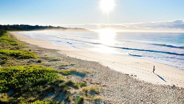 Ein Strand mit Kiesstrand, blauem Himmel und Sonnenschein.