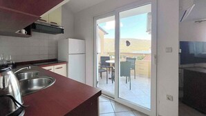 A compact kitchen with a refrigerator, sink, and a dining area with chairs and a table.